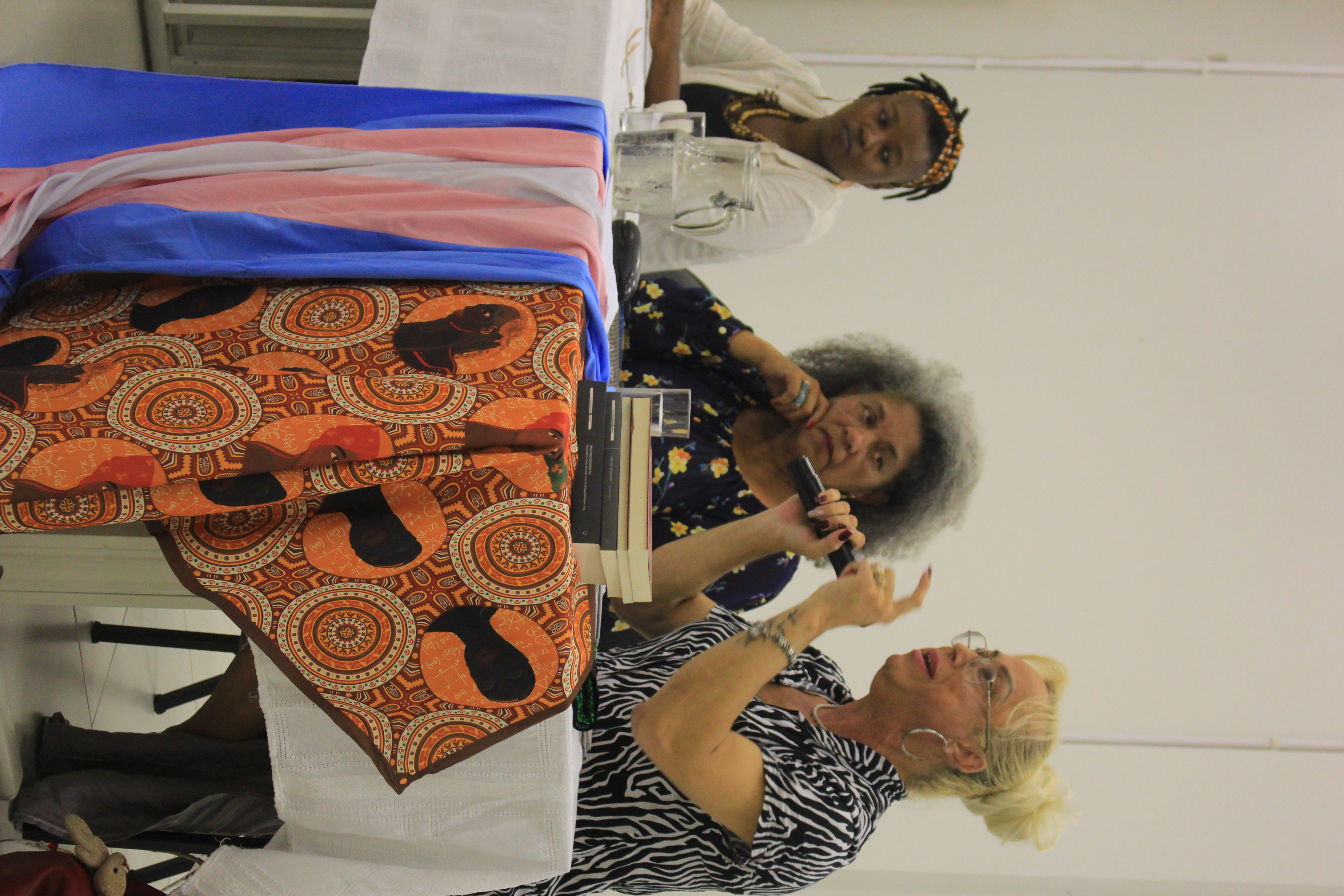 Sara mostra a bandeira transgênero e a capulana, símbolo do movimento negro