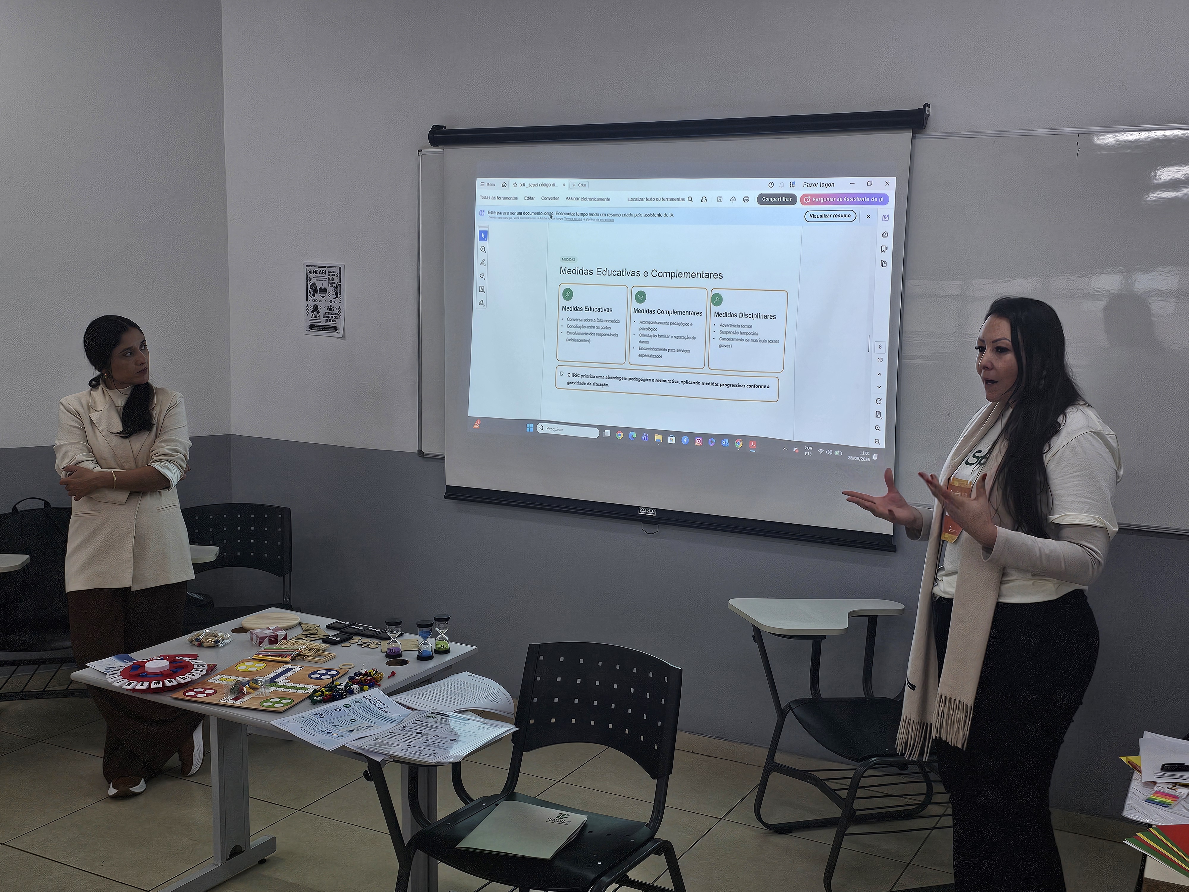 Bruna (à esq.), professora do Câmpus Palhoça Bilíngue, e Gleice, pedagoga em exercício na Reitoria, explicam sobre o Código de Convivência Discente (CDD)