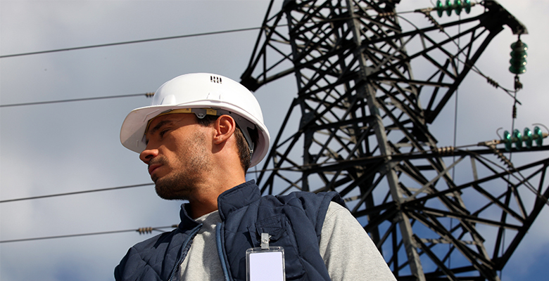 Engenheiro Eletricista junto a torres de retransmissão de energia elétrica
